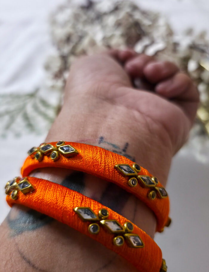 Handcrafted kundan bangles wrapped in orange silk thread