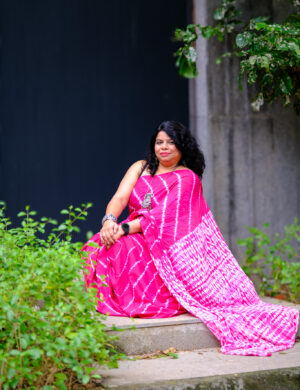 A pink Bandhej saree highlighting traditional craft captured in a natural setting.